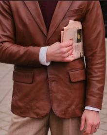 model holding newspaper and walking in the street with a brown mens leather jacket from Cycas d'Or
